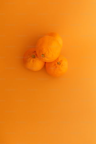 three oranges sitting on top of a yellow surface
