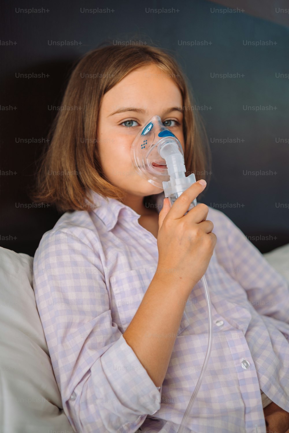 a little girl laying in bed with an inhaler in her mouth