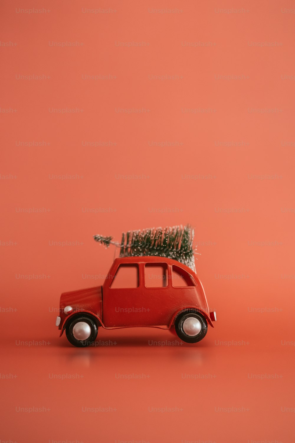 Una piccola auto rossa con un albero di Natale in cima