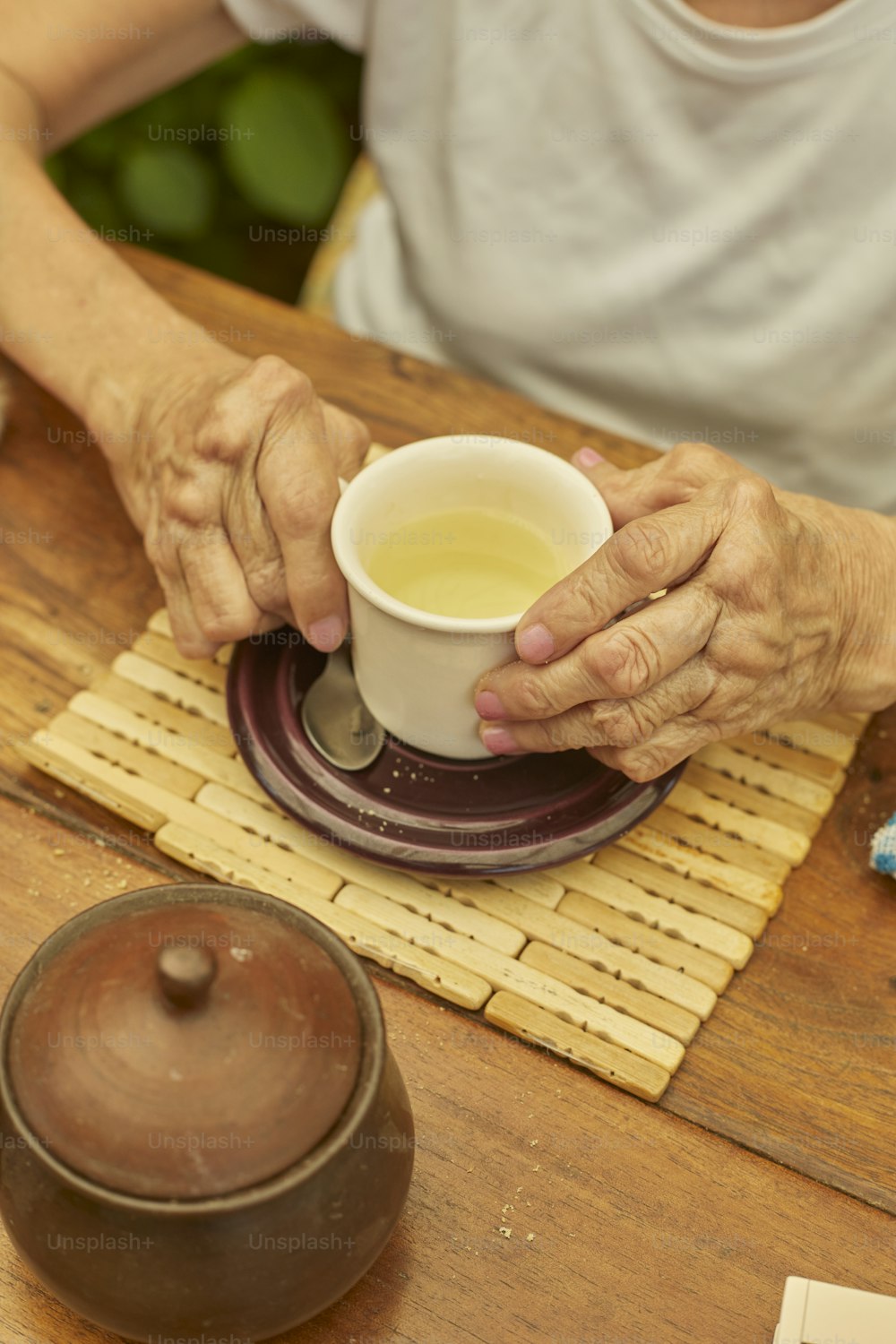 a woman holding a cup of tea on top of a wooden table
