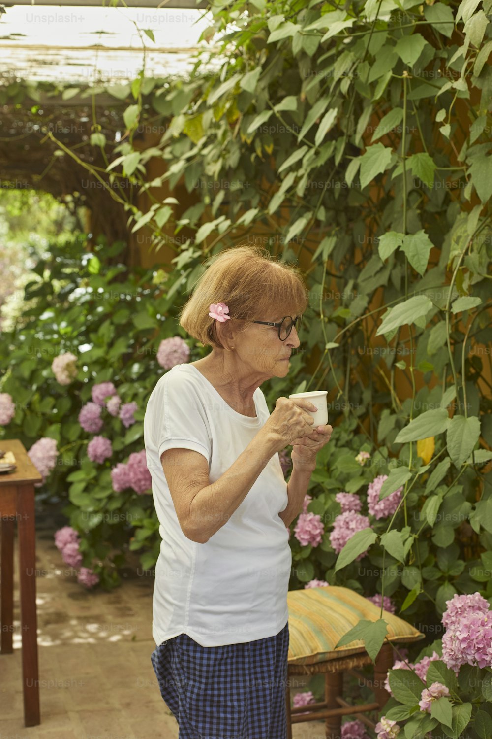 Una mujer parada en un invernadero sosteniendo una taza