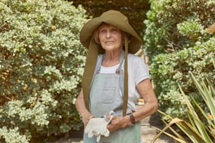 eine ältere Frau mit Hut und Gartenhandschuhen