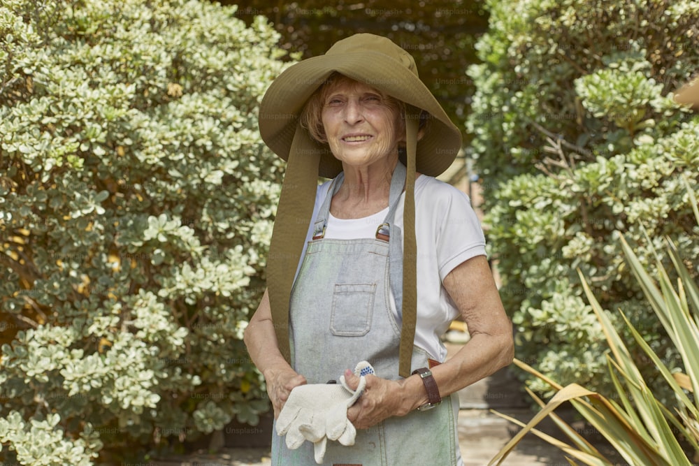 une femme âgée portant un chapeau et des gants de jardinage