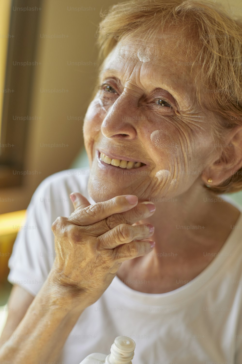 une femme âgée tenant un flacon de lotion