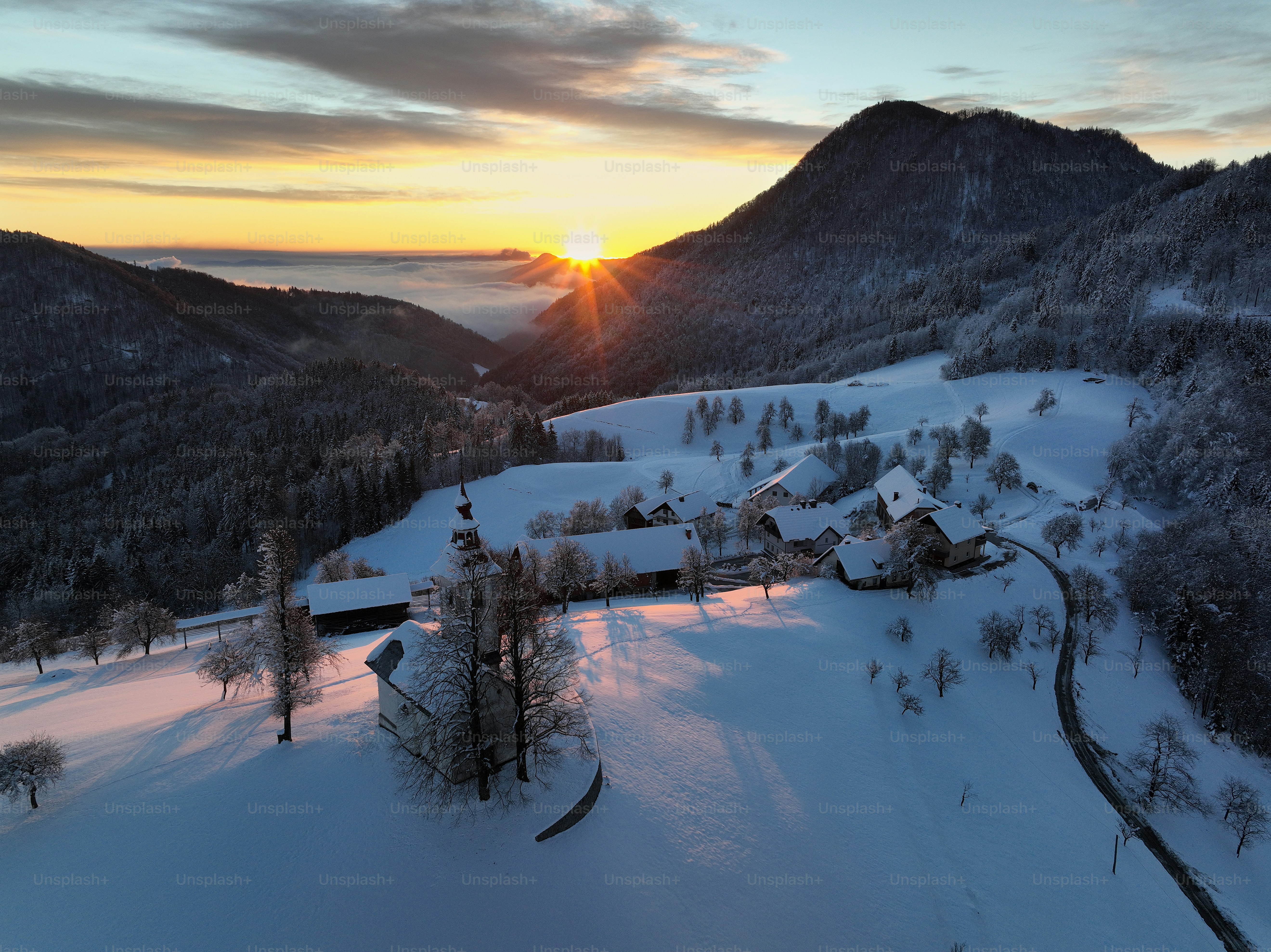 Die Sonne geht über einem verschneiten Bergdorf unter