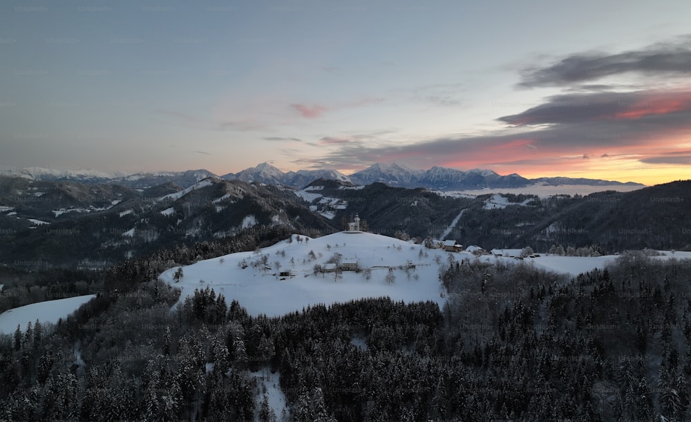 a view of a snowy mountain range at sunset