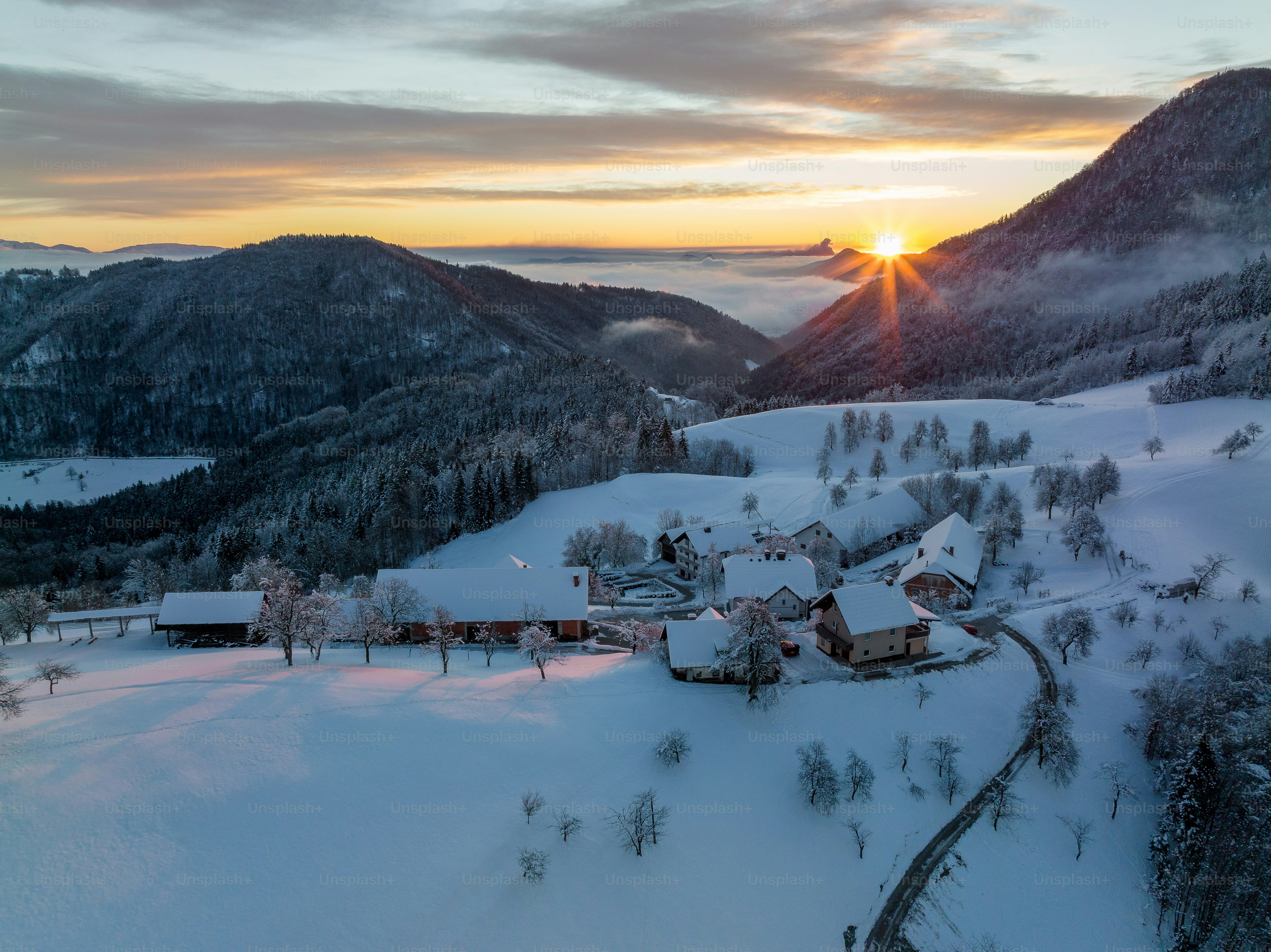 The sun is setting over a snowy mountain village photo – Sunset Image ...