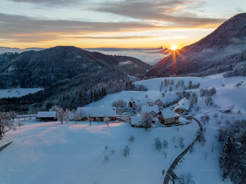 the sun is setting over a snowy mountain village