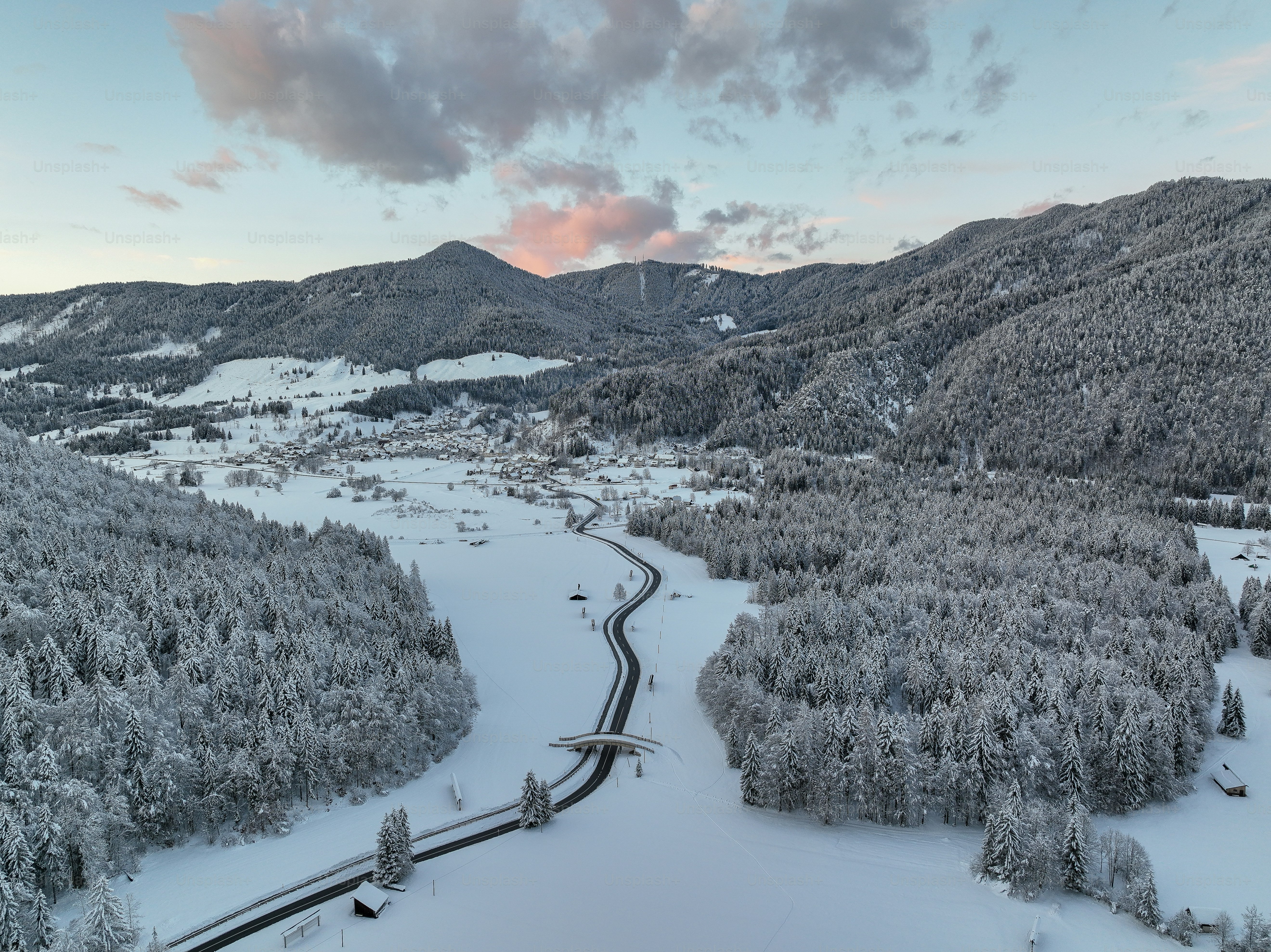 a winding road in the middle of a snow covered forest