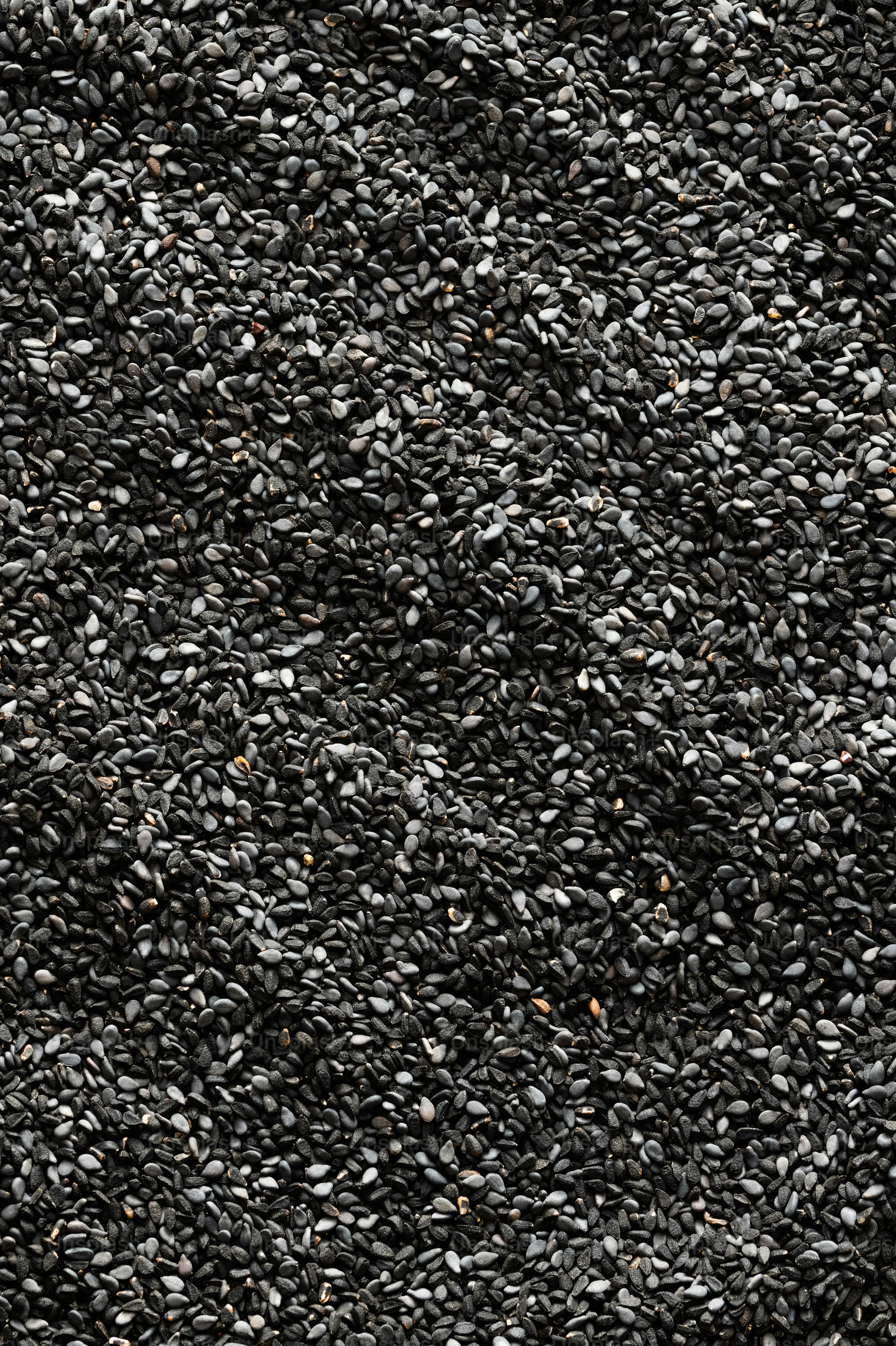 a pile of black sesame seeds on a white surface