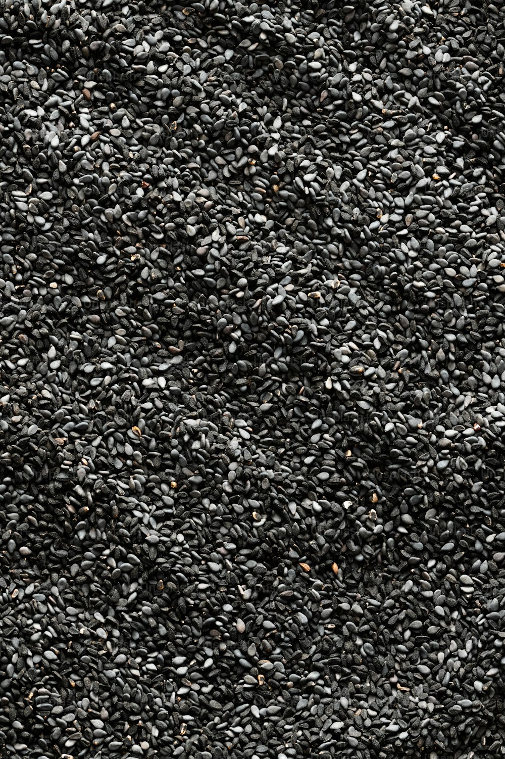 uma pilha de sementes de gergelim preto em uma superfície branca