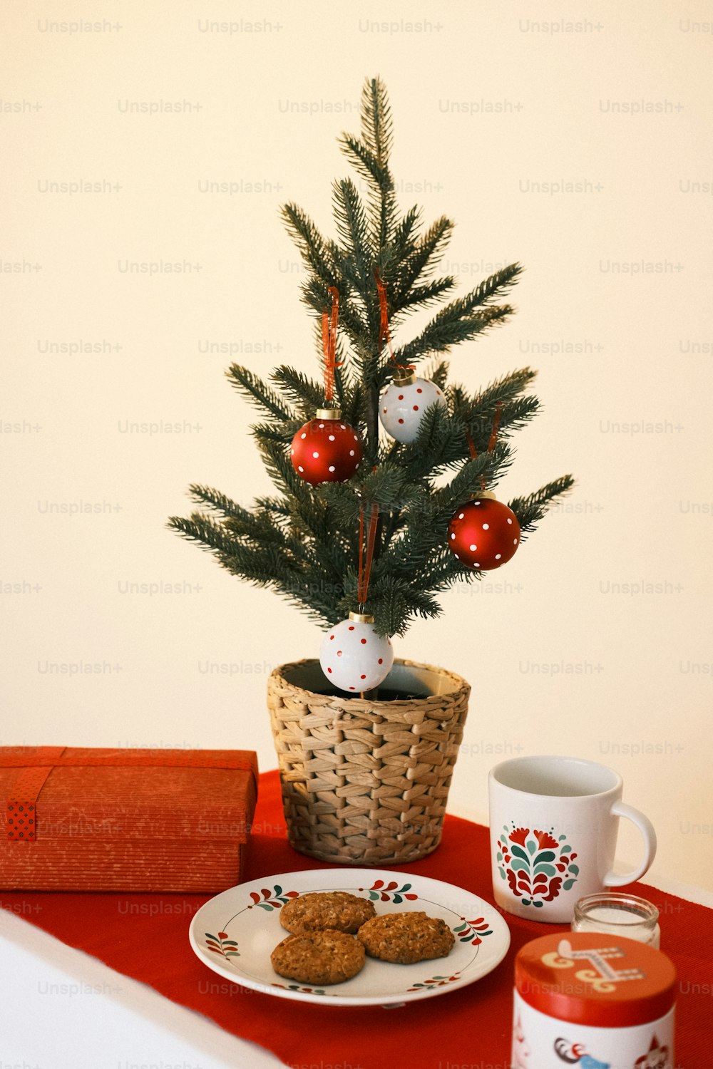 a small christmas tree in a basket next to a plate of cookies