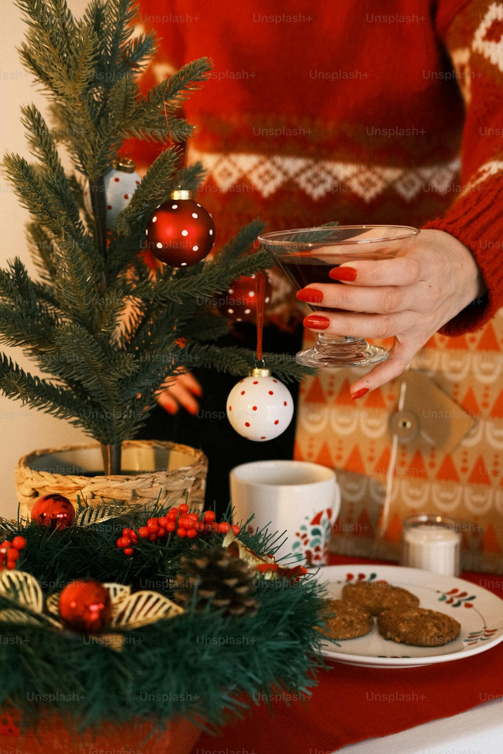 a woman holding a glass of wine in front of a christmas tree