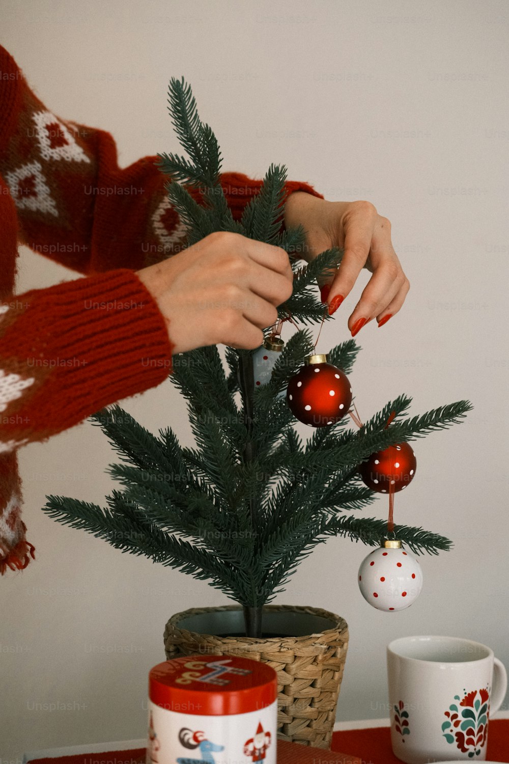 Una donna sta decorando un piccolo albero di Natale