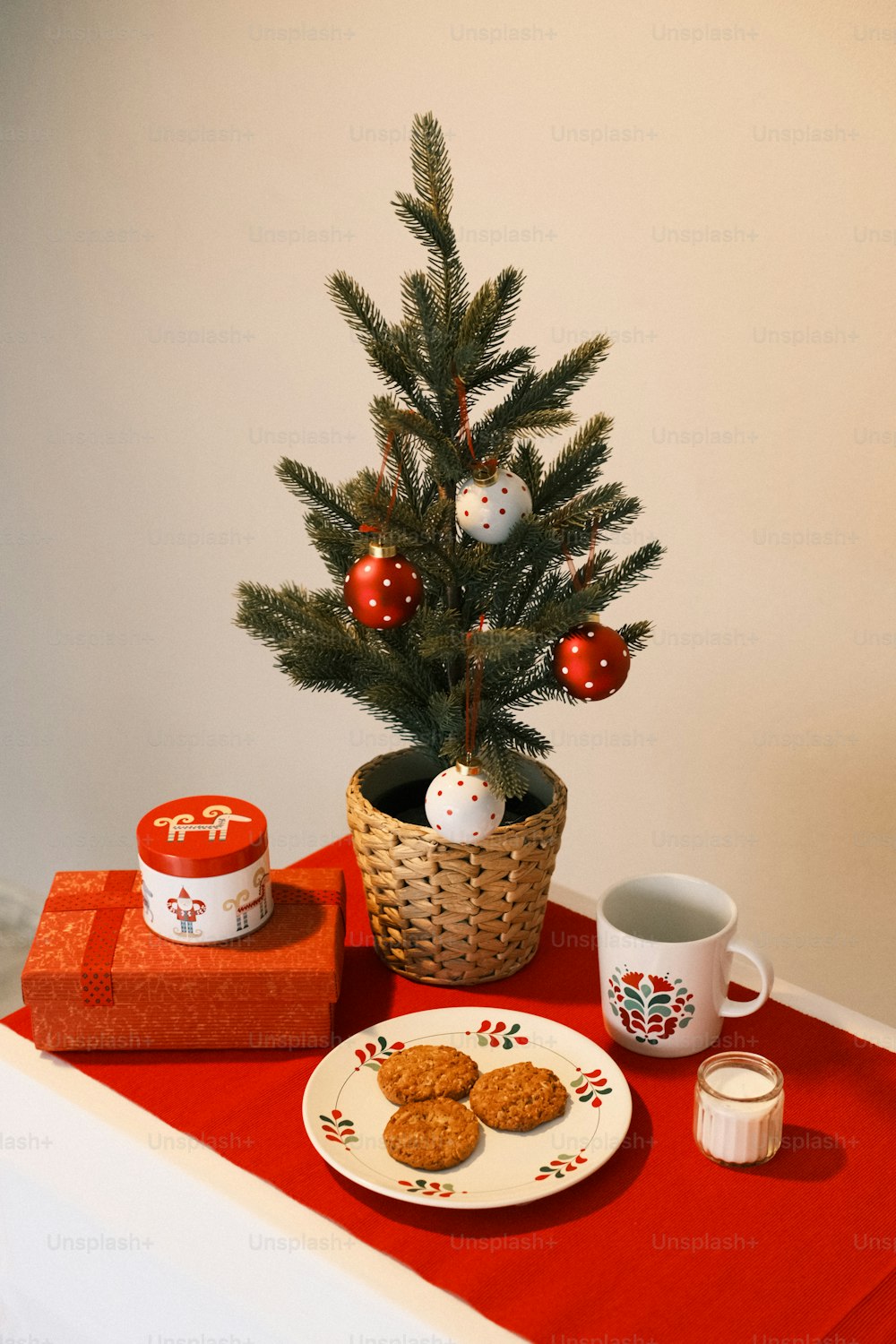a small christmas tree sits next to a plate of cookies
