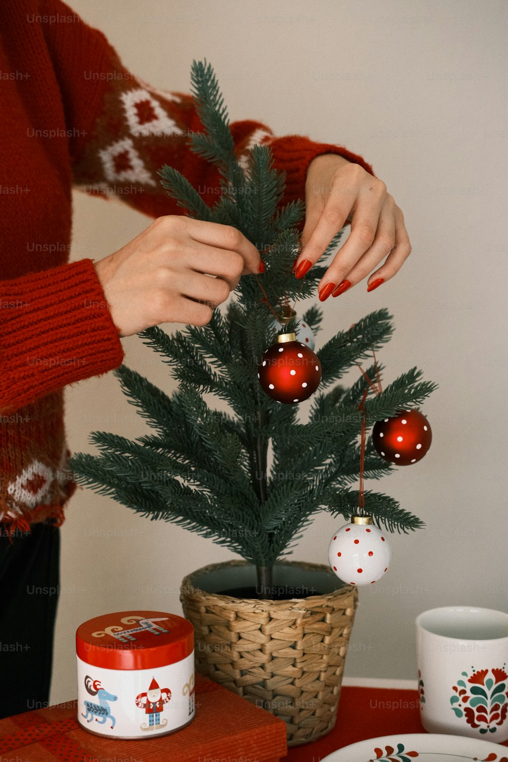 a woman decorating a small christmas tree