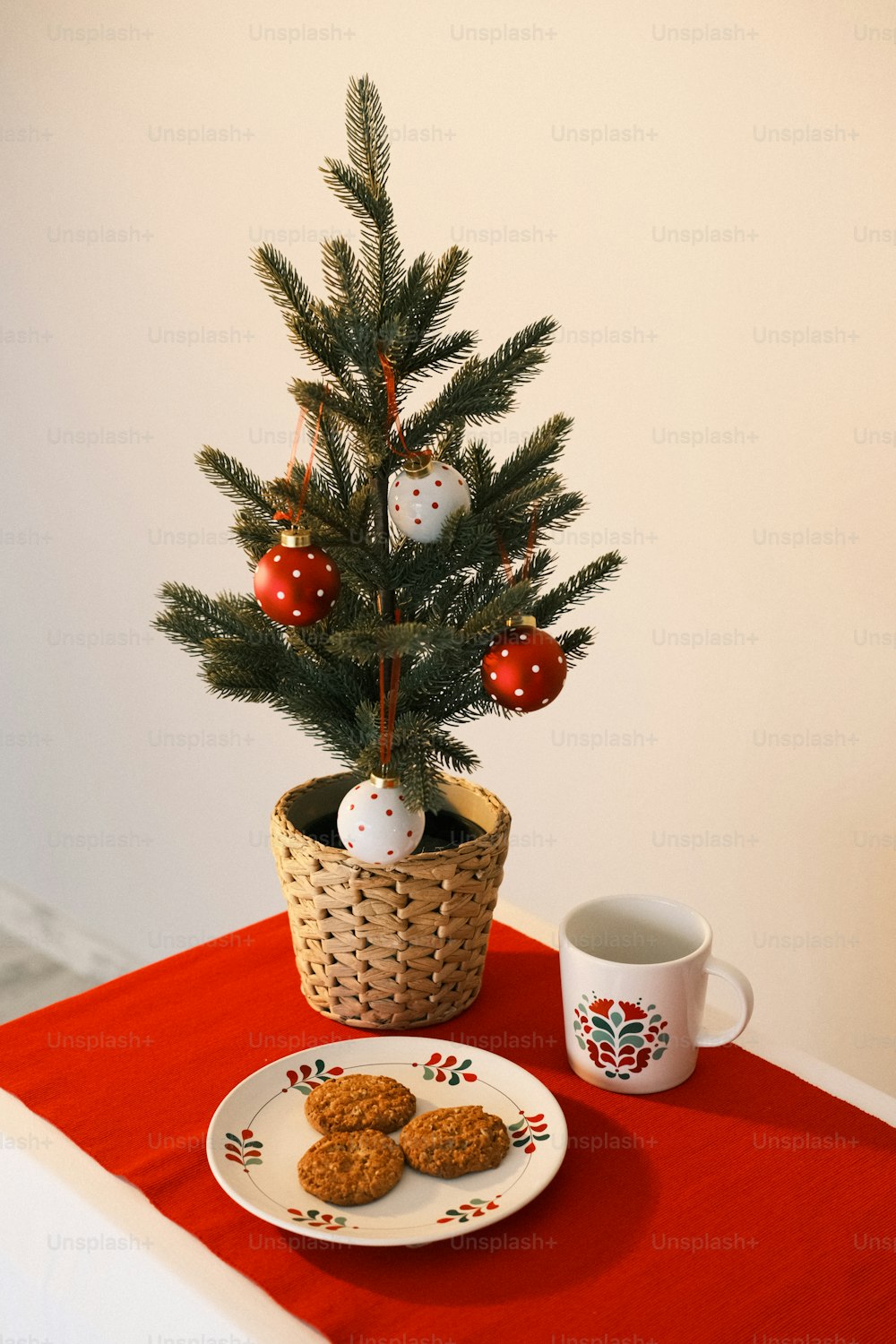 a small christmas tree in a basket next to a plate of cookies