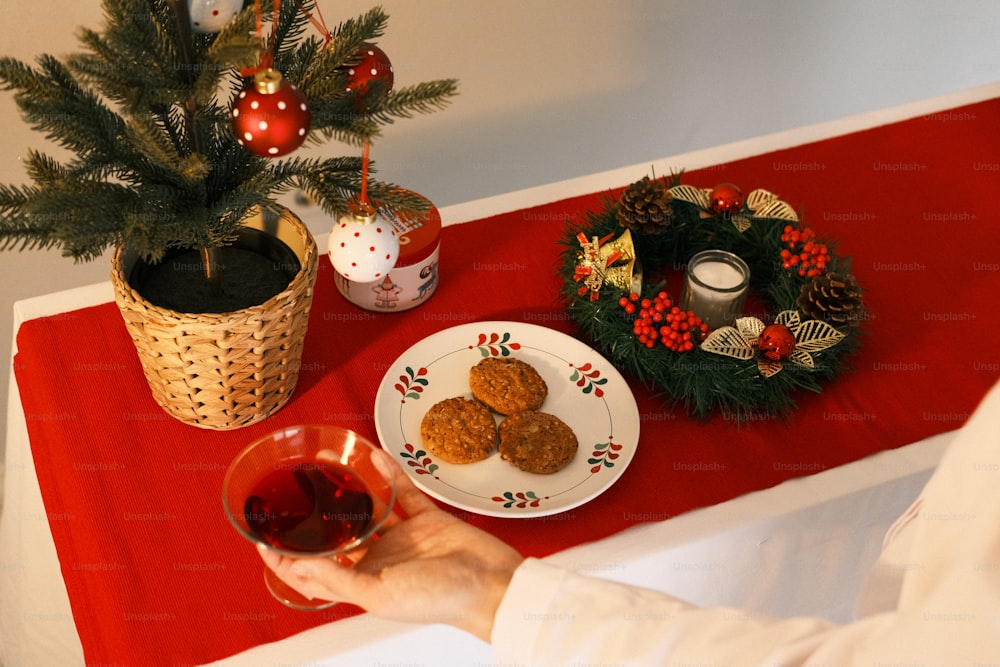 a person holding a glass of wine near a plate of cookies