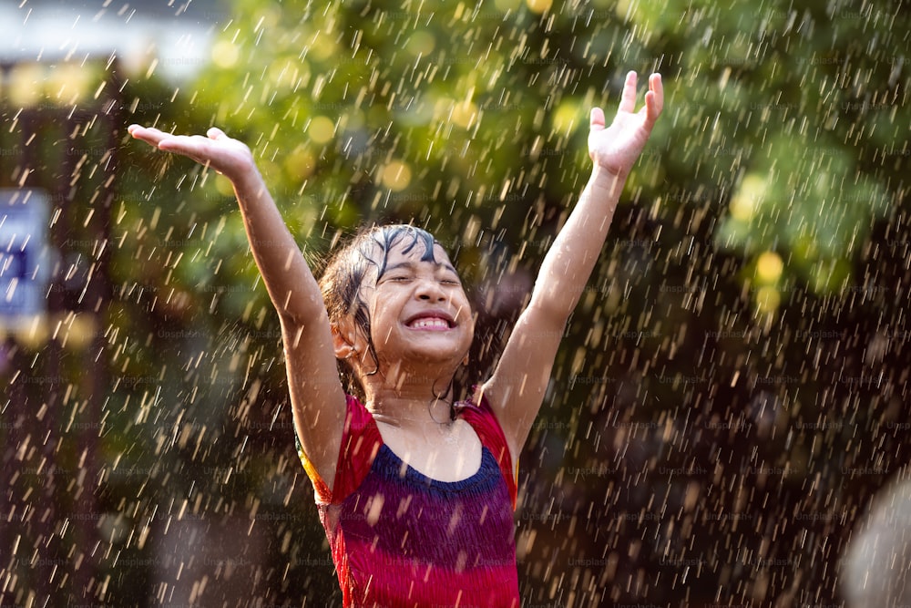 Asiatische Kinder, die im Regen spielen, sind glücklich.