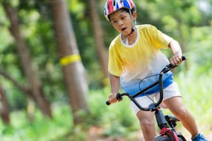 Il ragazzo asiatico si sta allenando per una felice mountain bike.