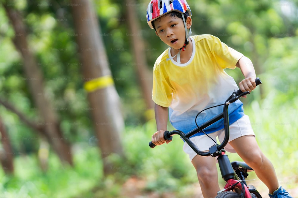 Un chico asiático está entrenando para un ciclismo de montaña feliz.