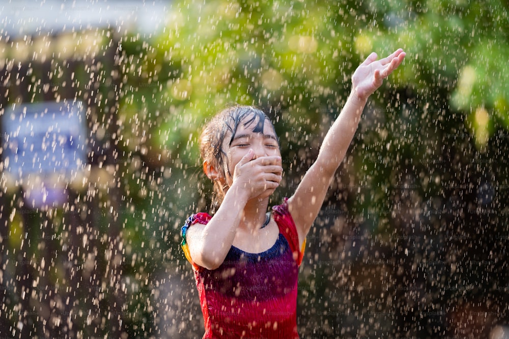 Los niños asiáticos que juegan bajo la lluvia son felices.