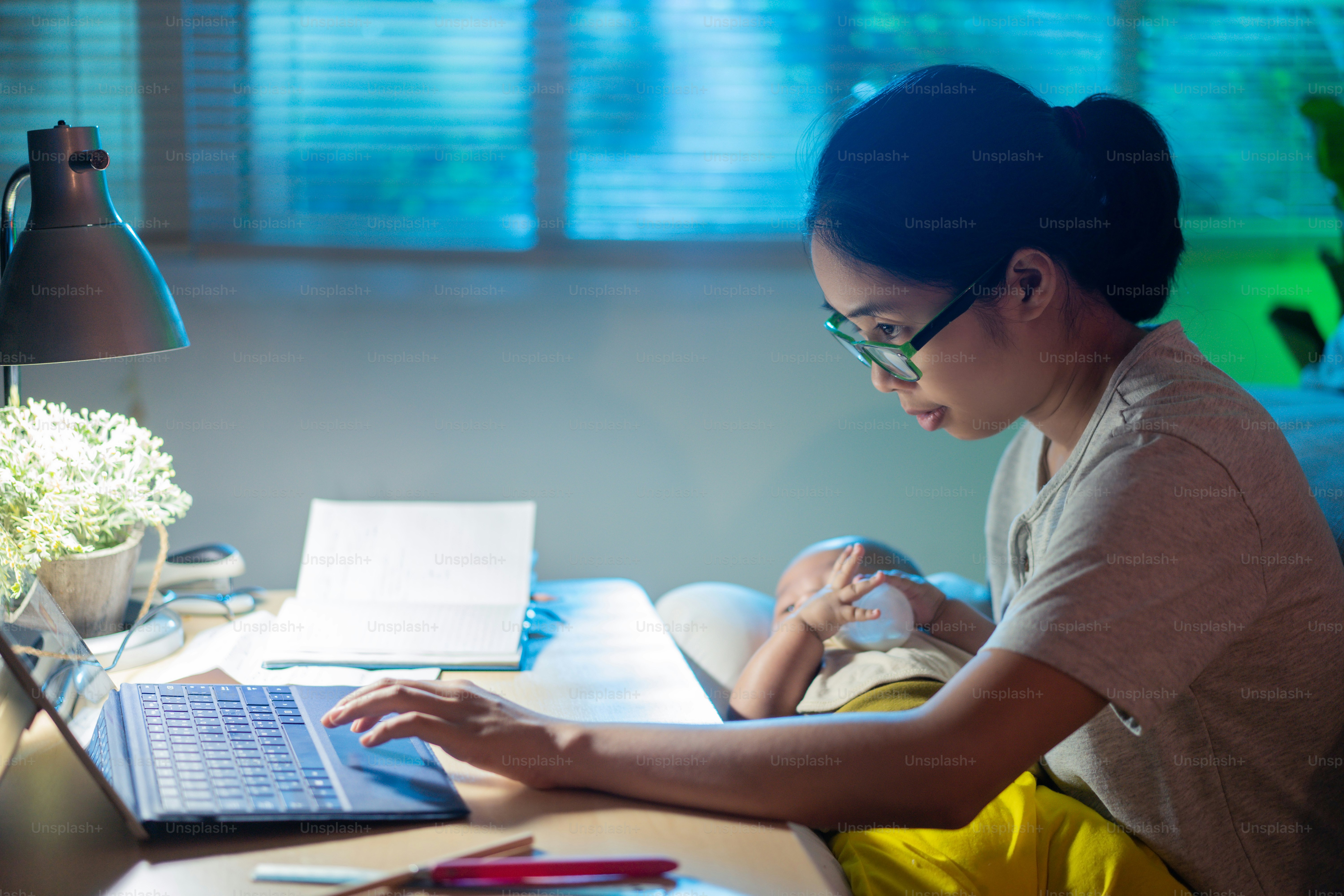 Asian mother and child Sitting and working at home at night, the mother is feeding the baby.