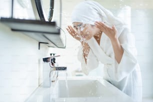 Donna asiatica che lava la faccia in bagno