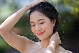 アジア人女性、彼女はシャワーを使って外で髪を洗います。彼女はリゾートで休んでいます。