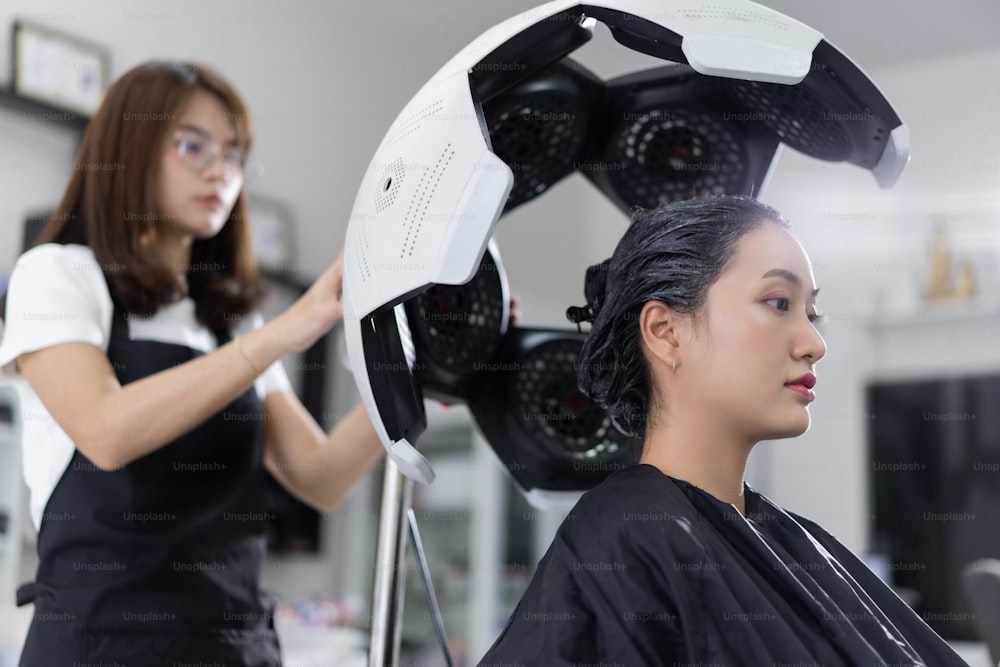 Asiatische Kosmetikerinnen färben Haare und machen Haare für customers.in Schönheitssalon