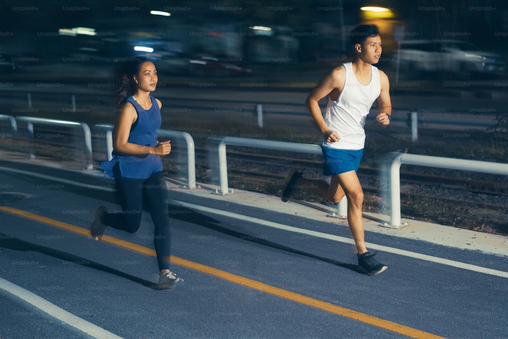 Asian couple jogging in the city streets at night