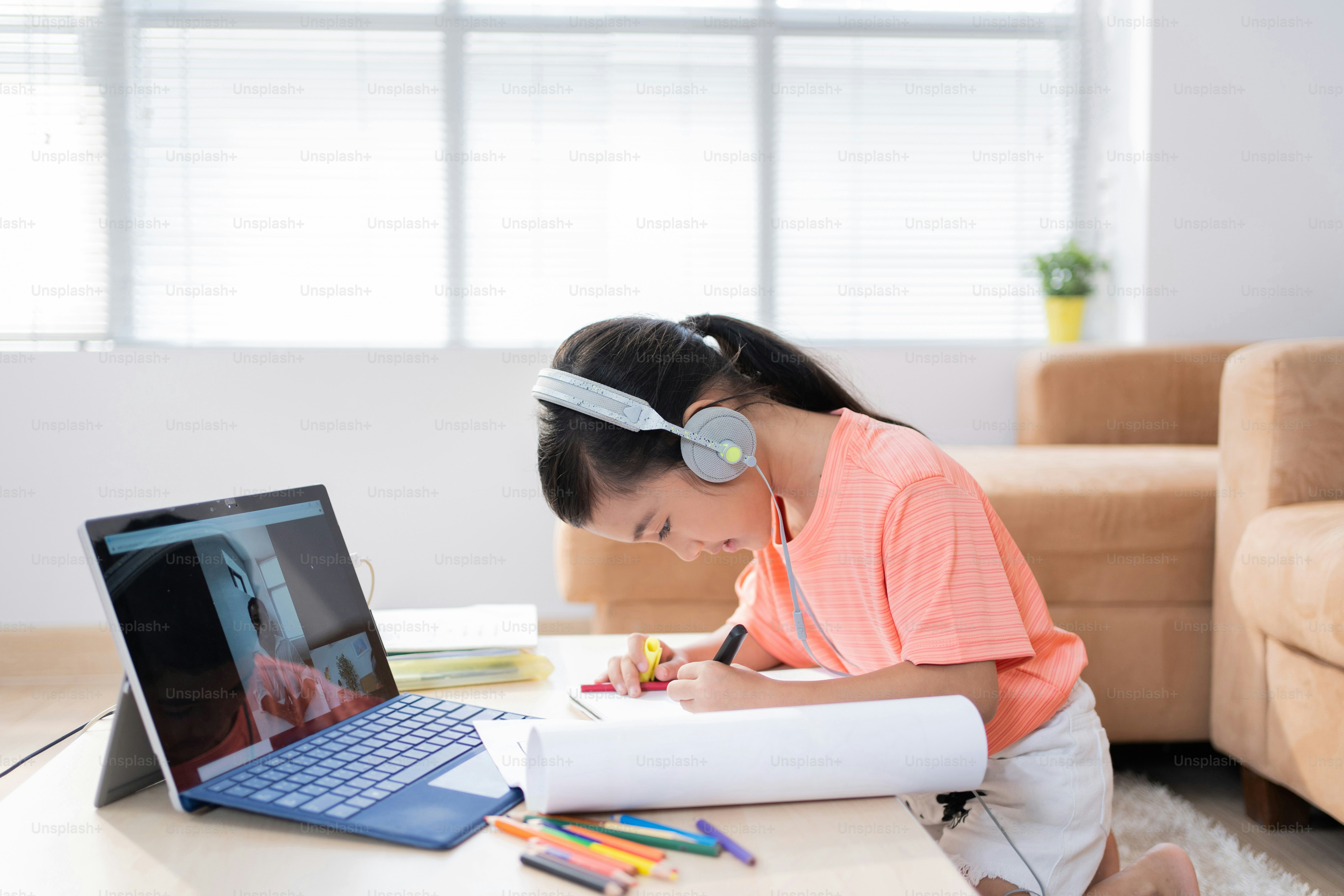 Asian girl is studying online at home. Asian girl is studying online at home. She shows the exercises to the teacher.