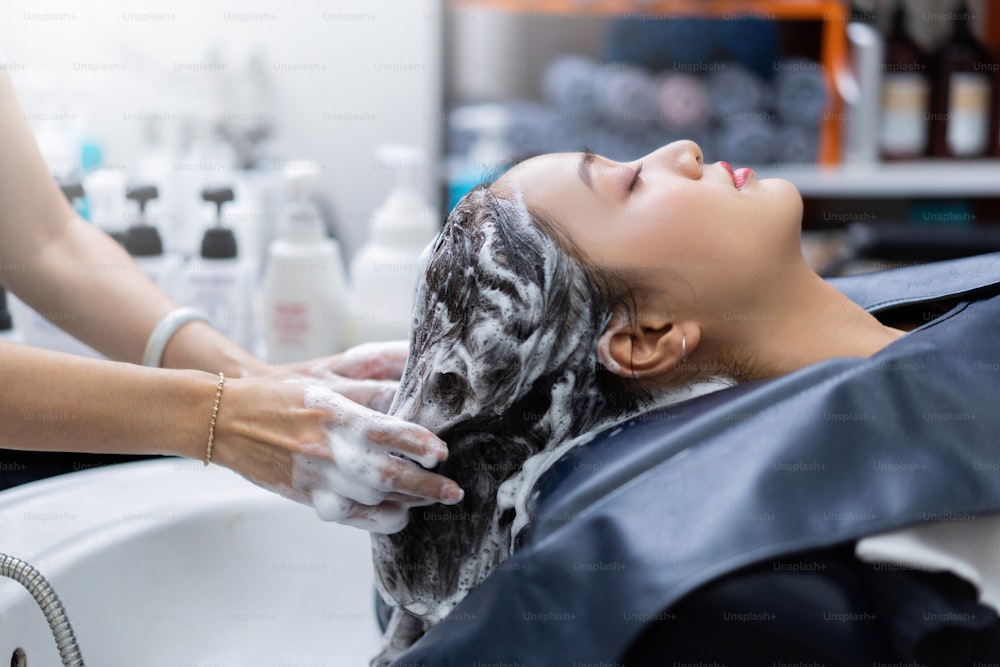 Beautician is washing her hair, is a beautiful woman. In a beauty salon