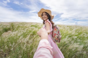 Lovers holding hands they come to travel on the meadow.