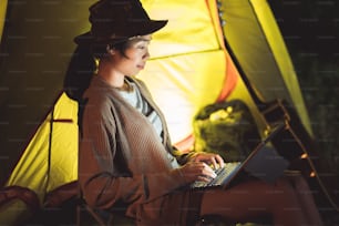 Le donne asiatiche che usano il computer comunicano durante il campeggio