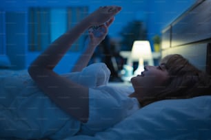 Asian woman using the phone social network at night she is in bed.