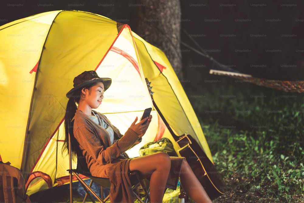 Asiatische Frauen, die Mobiltelefone benutzen, kommunizieren während des Campings