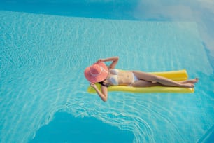 Belle femme, elle porte un bikini et dort sur un matelas pneumatique à la piscine d’été.