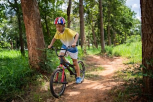 Il ragazzo asiatico si sta allenando per una felice mountain bike.