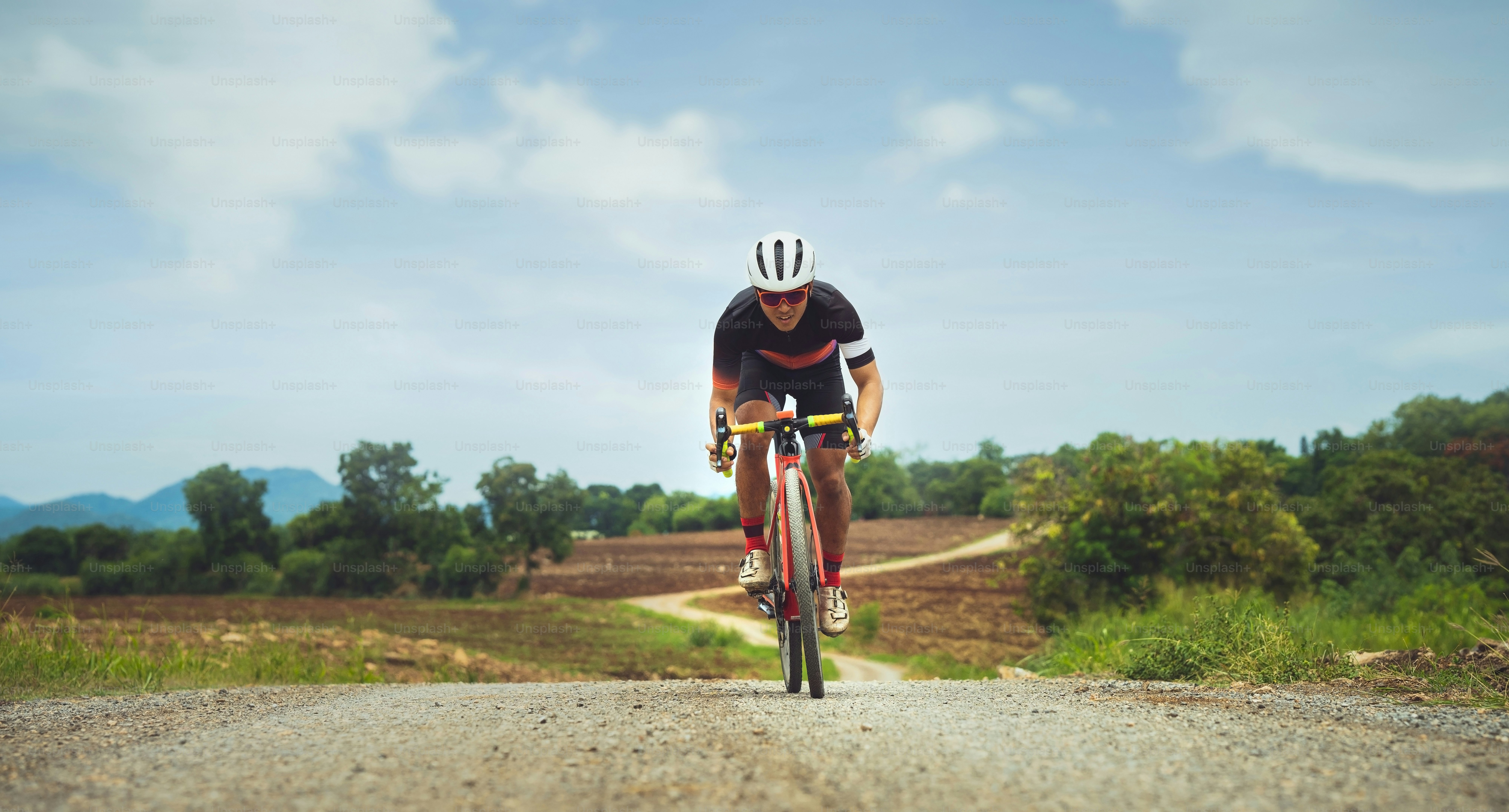 Hombre asiático en bicicleta por camino de grava.