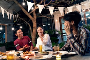 夜に家の外で冷たいビールを食べたり飲んだり、楽しい会話をするアジアのグループ