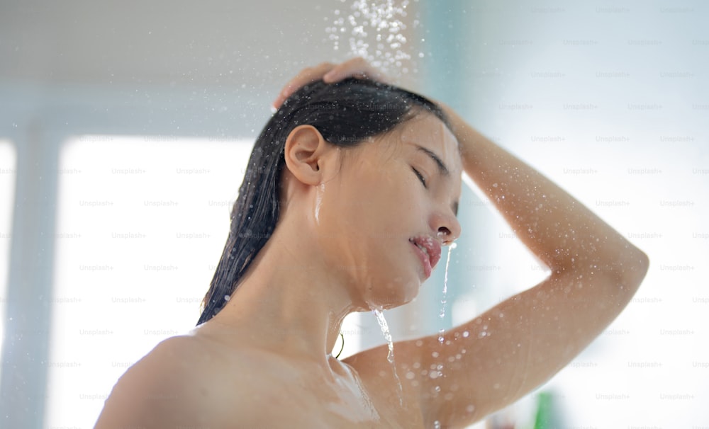 Femme asiatique Elle prend une douche et se lave les cheveux dans la salle de bain