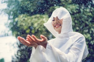 Donna asiatica è felice in un giorno di pioggia.