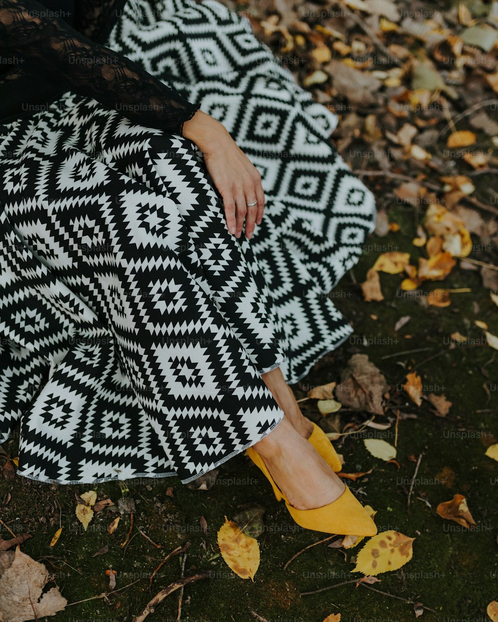 a woman sitting on the ground in a black and white skirt