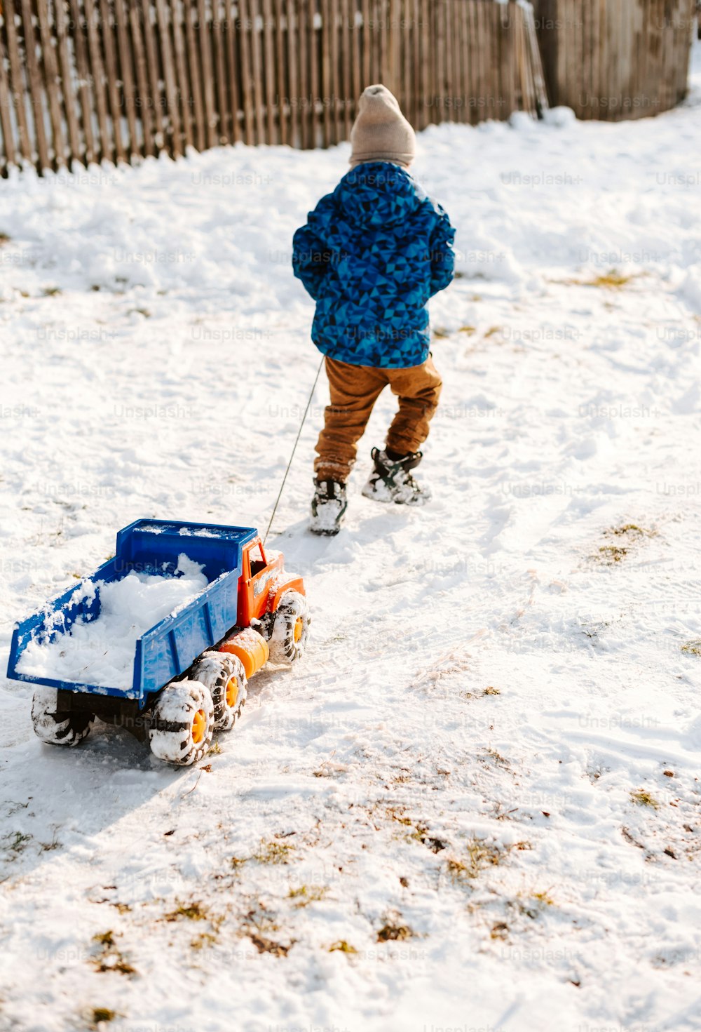 Un bambino piccolo che tira un camion giocattolo nella neve