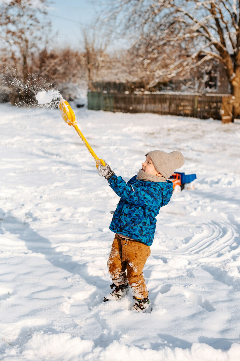 Un giovane ragazzo che gioca nella neve con un bastone