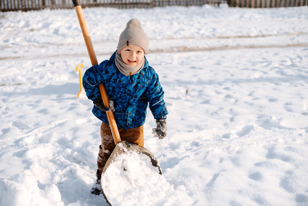 a young boy is shoveling through the snow