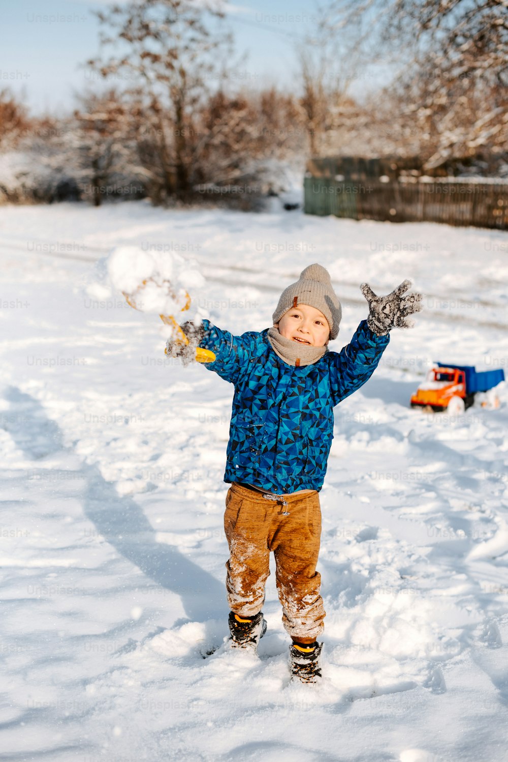 a little boy standing in the snow with his arms in the air