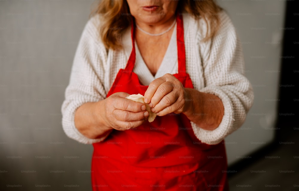 a woman in a red apron holding a piece of food