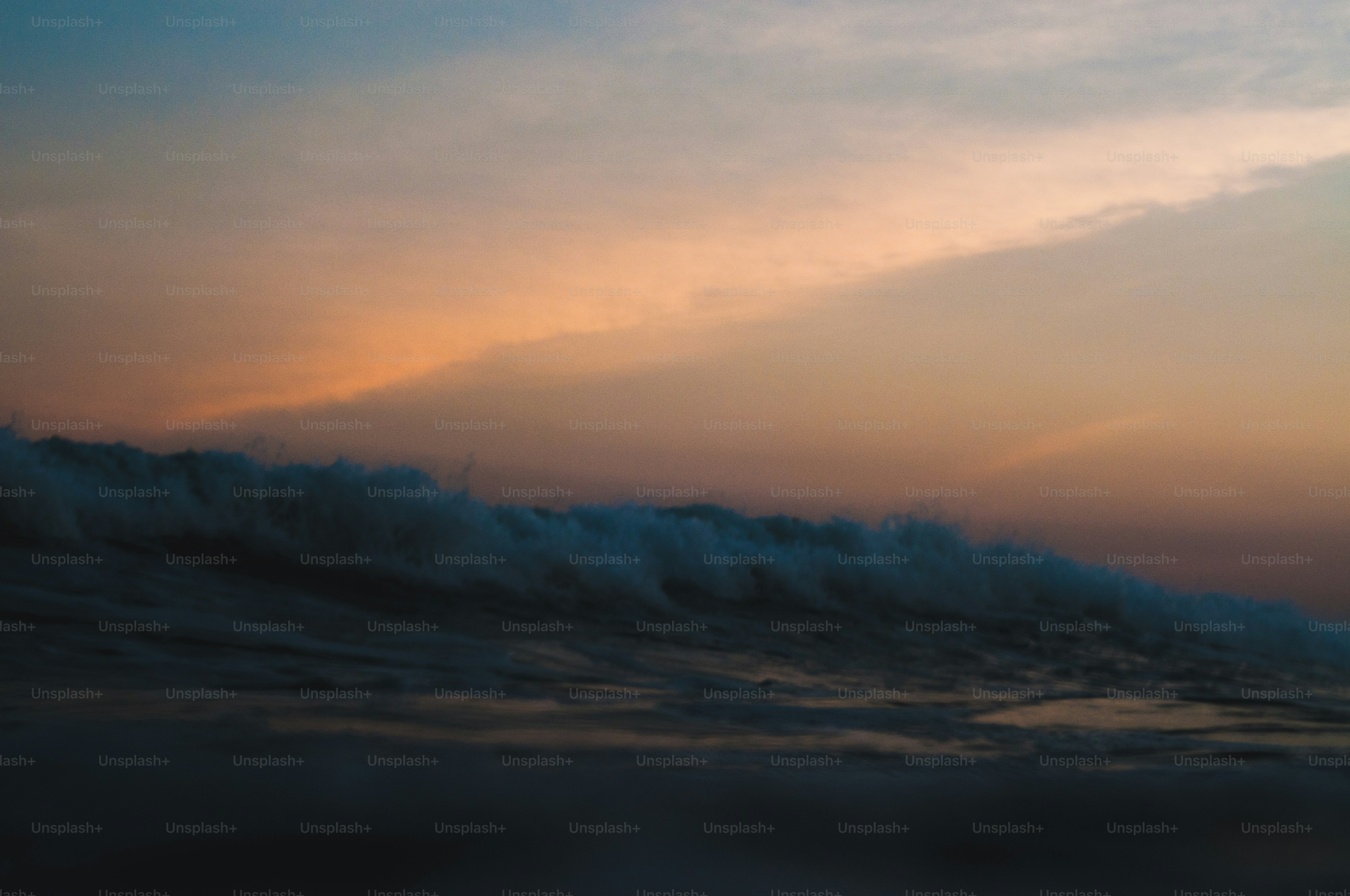 a large wave in the ocean with a sky background